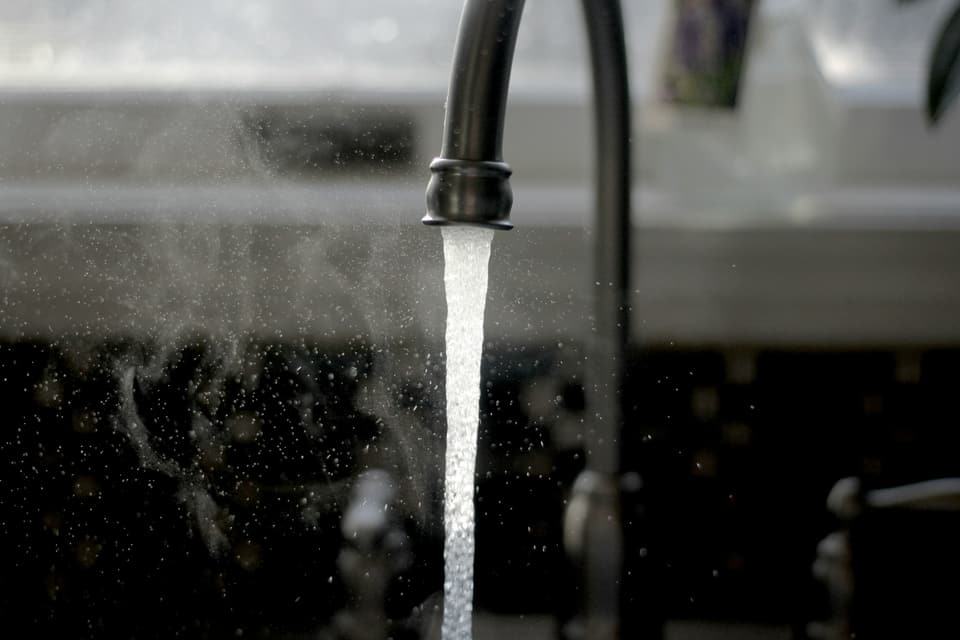 A stream of water running from a dark kitchen faucet