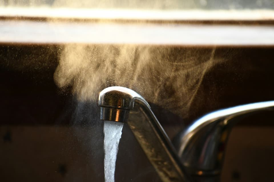 Steam rising from hot water running out of a kitchen faucet